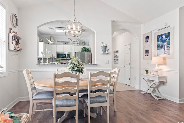 dining space featuring ornamental molding, a chandelier, vaulted ceiling, and hardwood / wood-style flooring