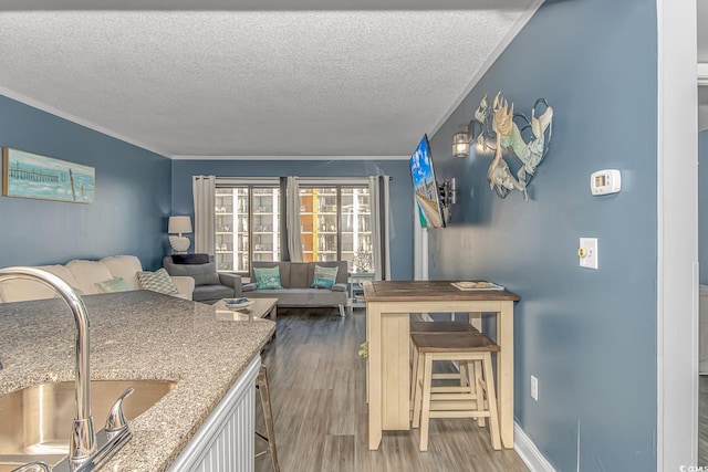 kitchen featuring hardwood / wood-style flooring, ornamental molding, sink, and a textured ceiling