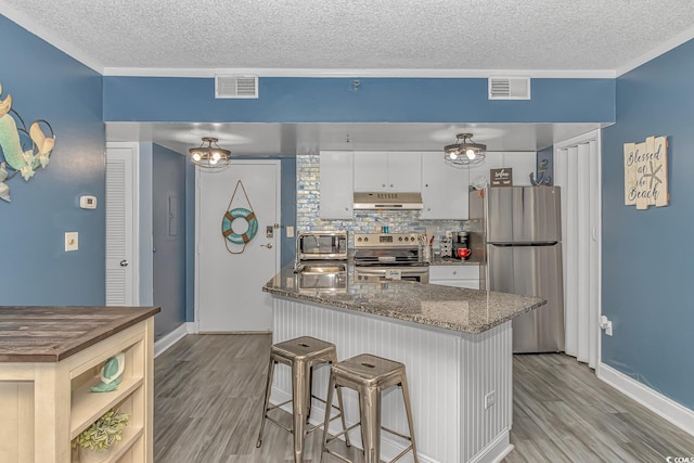 kitchen featuring sink, white cabinetry, light wood-type flooring, dark stone counters, and stainless steel appliances