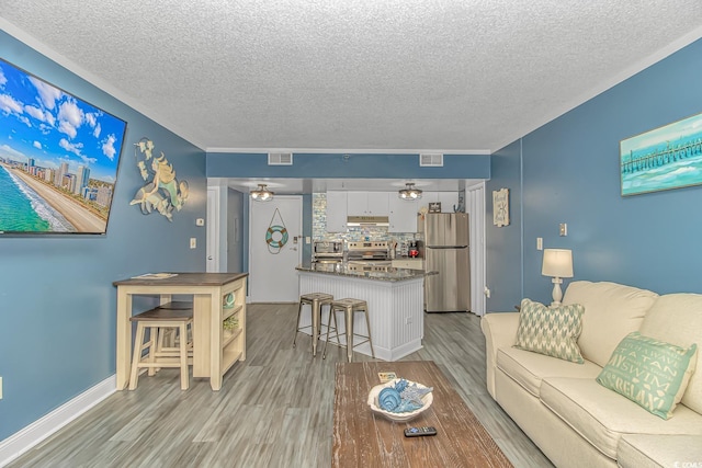 living room with a textured ceiling, ceiling fan, and light wood-type flooring