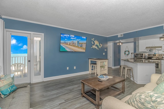 living room with hardwood / wood-style floors, ornamental molding, and a textured ceiling