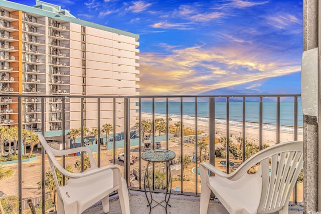 balcony at dusk with a water view and a beach view