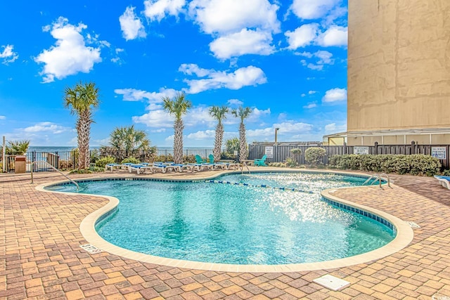 view of swimming pool with a patio area and a water view