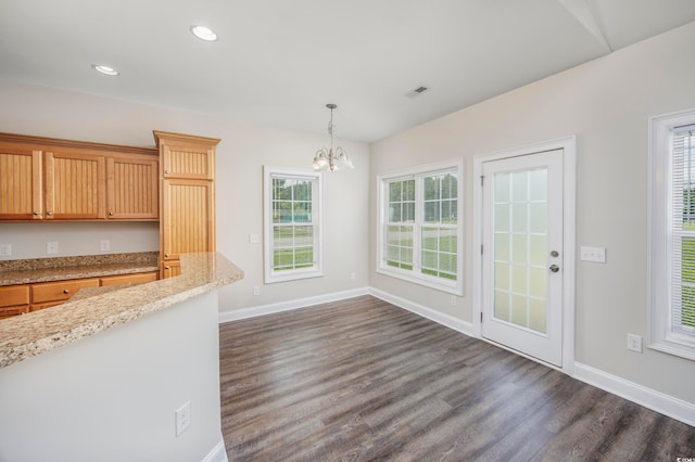 kitchen featuring light stone counters, pendant lighting, a notable chandelier, and dark wood-type flooring