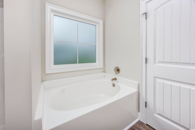 bathroom with a bath and hardwood / wood-style floors