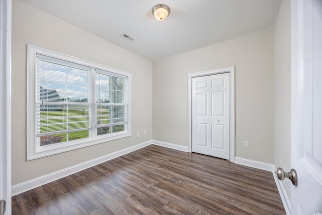 unfurnished bedroom featuring a closet and dark wood-type flooring