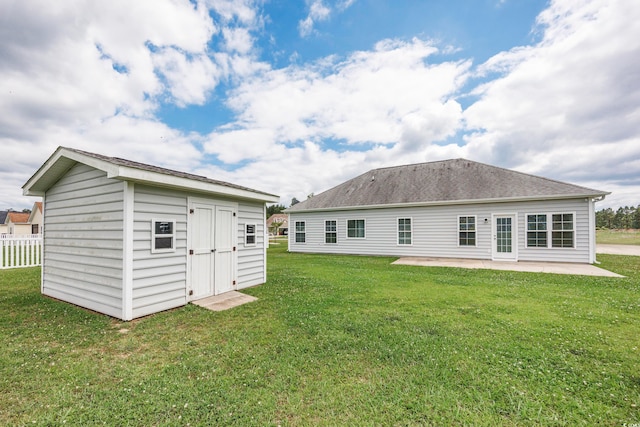 rear view of house with a storage shed, a patio, and a yard