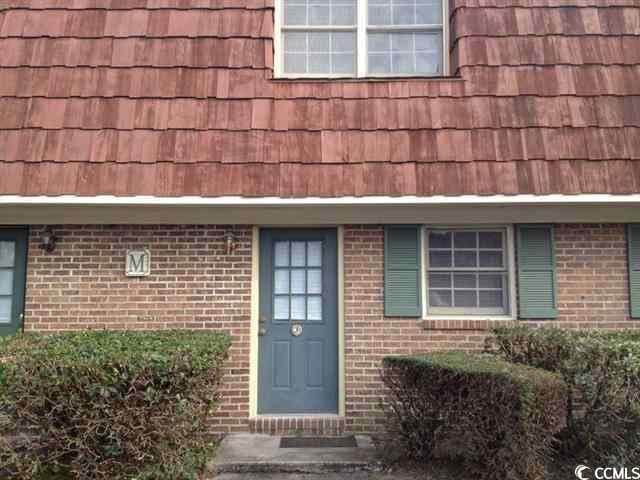 doorway to property featuring brick siding and mansard roof