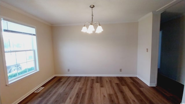 spare room with a wealth of natural light, ornamental molding, dark wood-type flooring, and a chandelier