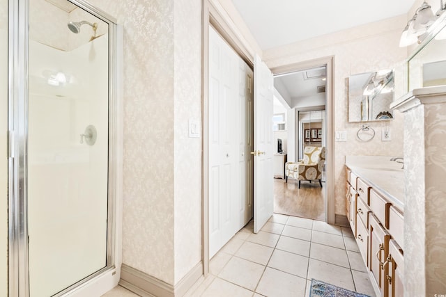 bathroom with a shower with door, vanity, and tile patterned floors