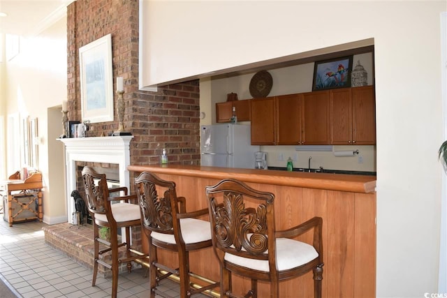 kitchen featuring white refrigerator, ornamental molding, and light tile patterned floors