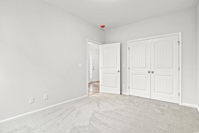 unfurnished bedroom with light carpet and a closet