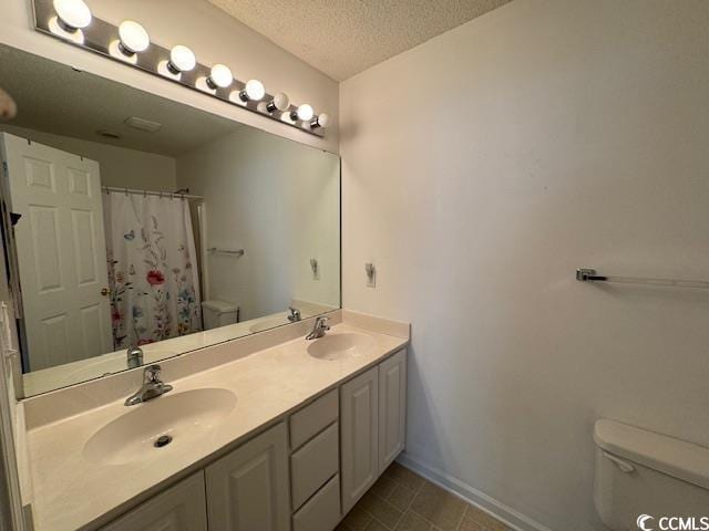 bathroom featuring a shower with curtain, vanity, toilet, and a textured ceiling