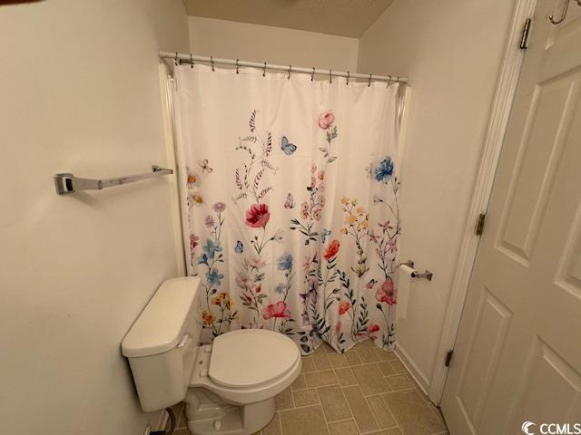 bathroom with a shower with shower curtain and toilet