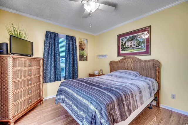 bedroom with ceiling fan, crown molding, light hardwood / wood-style floors, and a textured ceiling