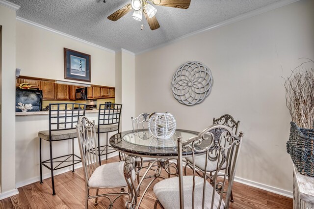 dining room featuring a textured ceiling, light hardwood / wood-style floors, and crown molding