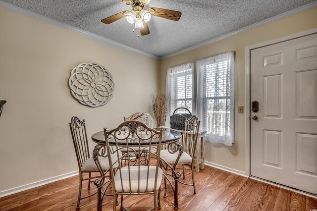 dining room with hardwood / wood-style floors, ceiling fan, crown molding, and a textured ceiling