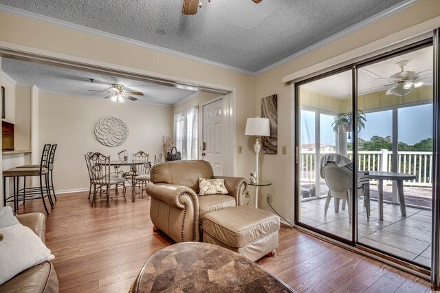 living room with crown molding, wood-type flooring, and a textured ceiling