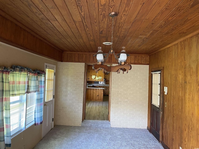 4155 Pinewood Dr, Mullins, SC 29574 - empty room with wood ceiling, brick wall, wooden walls, an inviting chandelier, and carpet floors