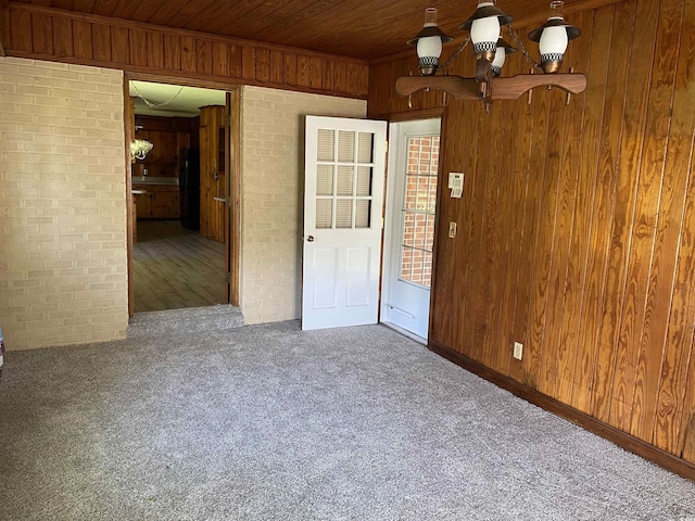 4155 Pinewood Dr, Mullins, SC 29574 - empty room featuring dark colored carpet, wooden ceiling, wood walls, and brick wall