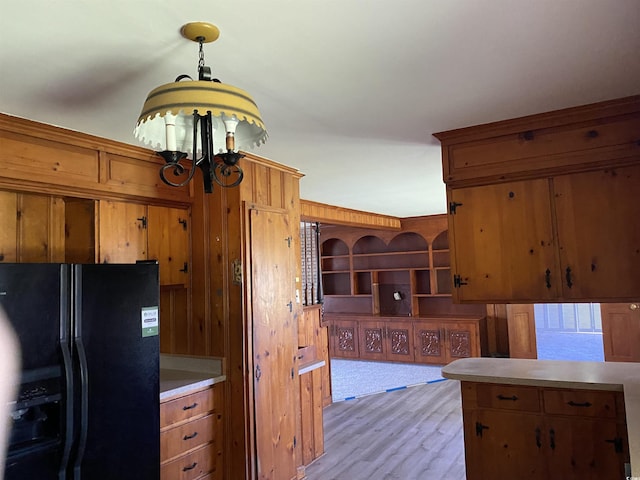 4155 Pinewood Dr, Mullins, SC 29574 - kitchen with hanging light fixtures, a chandelier, wooden walls, black fridge with ice dispenser, and light wood-type flooring