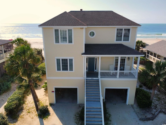 view of front of home with a view of the beach, a garage, a porch, and a water view