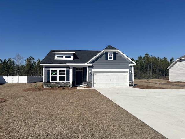 craftsman-style house featuring an attached garage, fence, stone siding, concrete driveway, and a gate