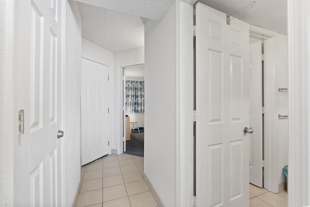 corridor with light tile patterned floors and a textured ceiling