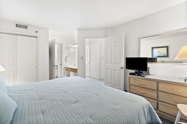 bedroom featuring ensuite bathroom, a textured ceiling, and a closet