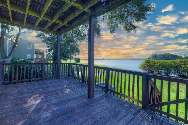 deck at dusk featuring a lawn and a water view