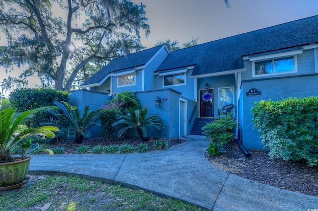 view of front of house with stucco siding and roof with shingles