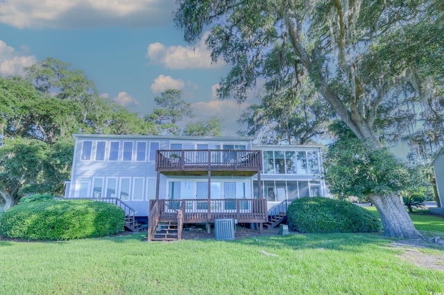 rear view of house with a deck, a yard, and a sunroom