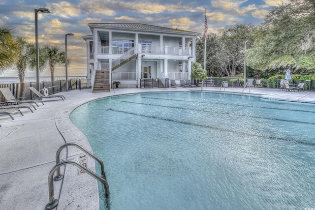 pool at dusk with a patio area