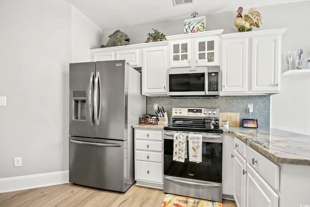 kitchen featuring light hardwood / wood-style flooring, appliances with stainless steel finishes, light stone countertops, white cabinets, and decorative backsplash