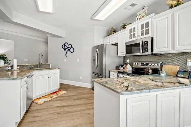 kitchen with appliances with stainless steel finishes, sink, white cabinets, and kitchen peninsula