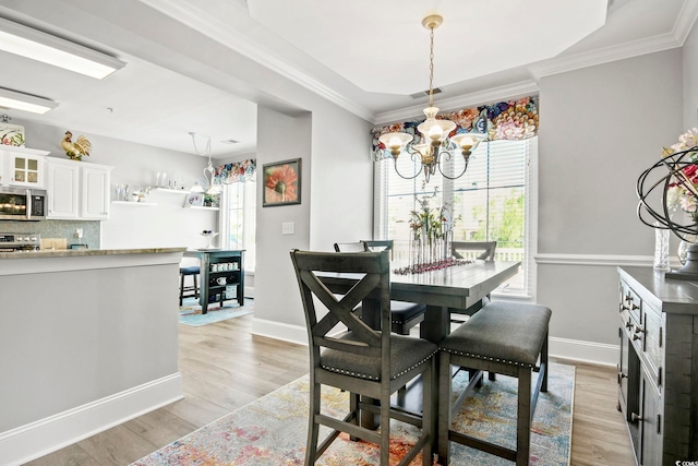 dining room with a notable chandelier, ornamental molding, and light wood-type flooring