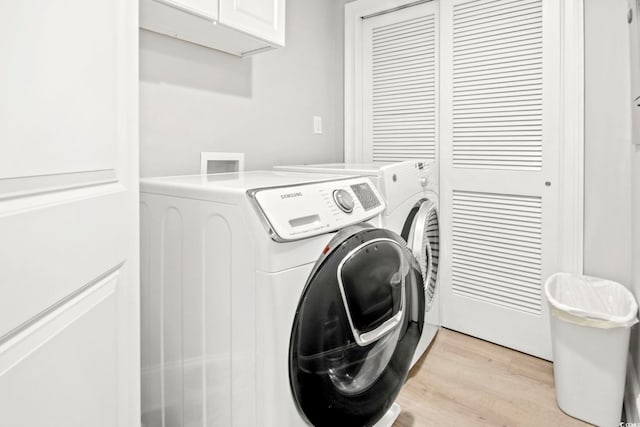 clothes washing area featuring cabinets, independent washer and dryer, and light wood-type flooring