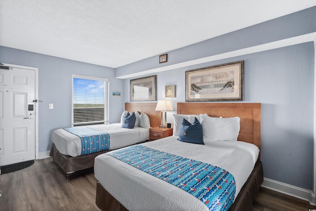 bedroom featuring a textured ceiling, dark wood-type flooring, and baseboards