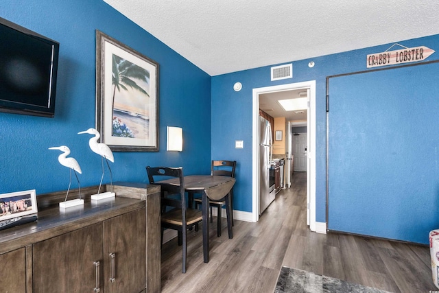 office featuring a textured ceiling, wood finished floors, visible vents, and baseboards