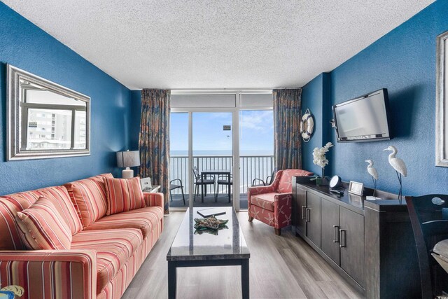 living area featuring a textured ceiling, light wood-style floors, and a textured wall