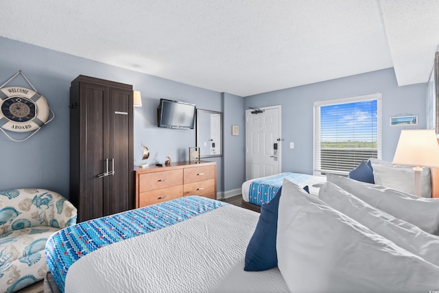 bedroom featuring wood finished floors, baseboards, and a textured ceiling