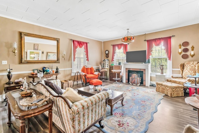 living room featuring crown molding, hardwood / wood-style floors, and a brick fireplace