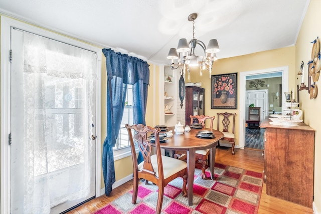 dining area featuring a notable chandelier, built in features, and wood-type flooring