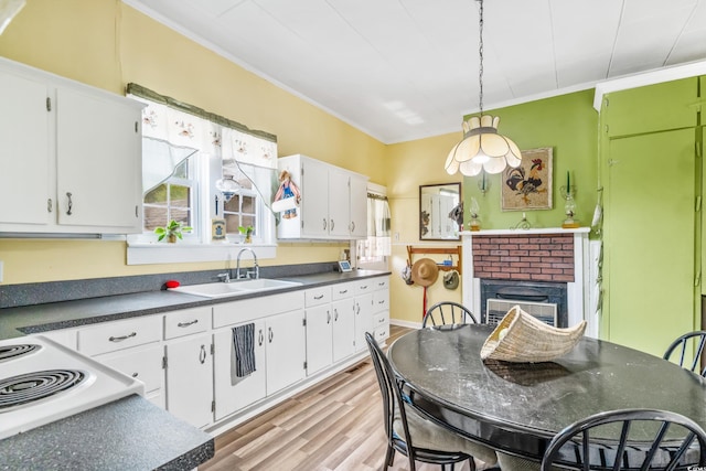 kitchen featuring sink, a brick fireplace, crown molding, white cabinets, and light wood-type flooring