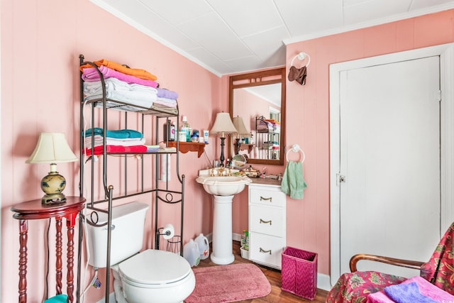 bathroom with wood-type flooring, toilet, crown molding, and sink