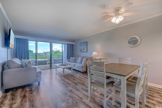 dining area featuring baseboards, crown molding, a ceiling fan, and wood finished floors