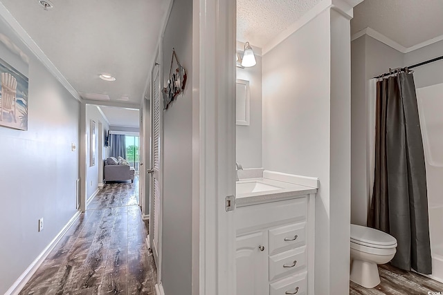 full bath featuring toilet, wood finished floors, vanity, baseboards, and crown molding