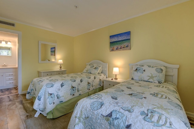 bedroom featuring baseboards, visible vents, wood finished floors, and ornamental molding