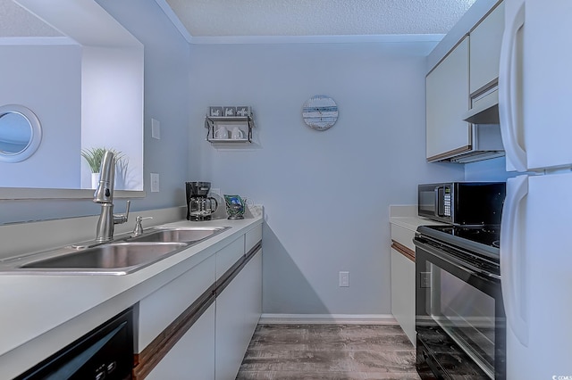 kitchen with freestanding refrigerator, light countertops, black range with electric cooktop, white cabinetry, and a sink