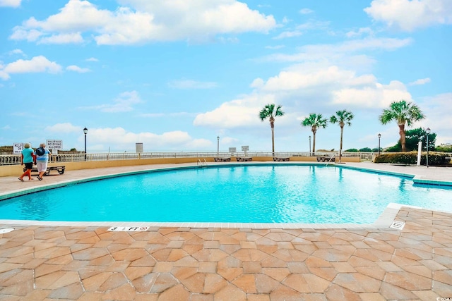 community pool with a patio and fence